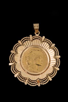 un gros plan d'une pièce de monnaie sertie dans un pendentif en or, sur fond noir