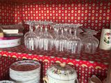de nombreux verres et assiettes rangés sur une étagère dans la cuisine