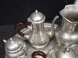 a silver tray with silver teapots and other silverware on it