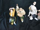 five figurines of people sitting on a black cloth