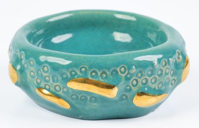 a green bowl with gold handles on a white surface