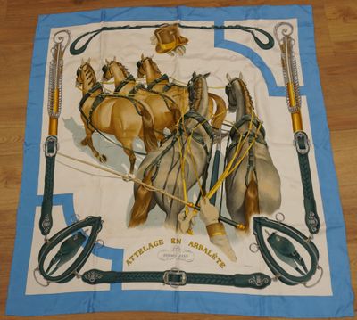 une écharpe bleue et blanche sur laquelle figurent des chevaux tirant une calèche