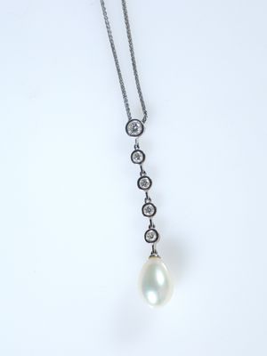 Un pendentif composé d'une perle blanche et de diamants est suspendu à une chaîne en argent