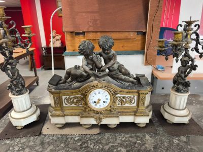 a clock sitting on top of a table surrounded by statues