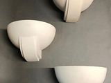 three white bowls are on a gray surface with a black background