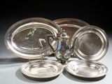 quatre assiettes en argent et une théière en argent posées sur une table