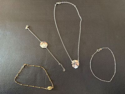 quatre colliers et bracelets différents posés sur un fond noir