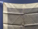 une photo d'un foulard carré noir et blanc suspendu à une corde à linge