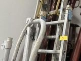 a ladder that is leaning against a wall next to a pile of pipes