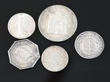 six different british silver coins on a black surface