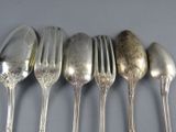five silver spoons and a fork on a table