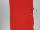 un gros plan d'un t-shirt rouge posé sur une surface blanche