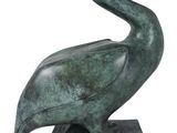 a green statue of a pelican sitting on top of a base