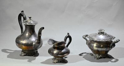 trois théières en argent et deux tasses en argent posées sur une table