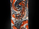 un vase orange et noir posé sur une surface noire