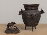 a bronze vase and a figurine sitting on a table