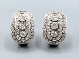une paire de boucles d'oreilles en or blanc et diamants sur fond bleu