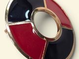 an image of a red, black and white broochle on a white surface