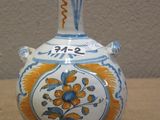 a blue and yellow vase sitting on a table next to a wall