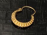 une image d'une paire de boucles d'oreilles en or sur une surface noire