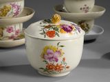 many bowls and cups with flowers on them on a table