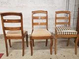 Trois chaises en bois sont alignées contre un mur de briques blanches