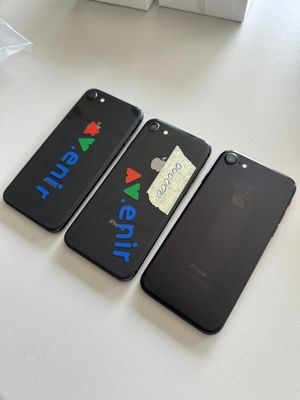 three black iphones sitting on top of a table next to each other