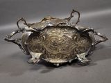 an antique silver plate with two birds on it on a gray background