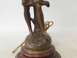 an antique bronze statue of a woman holding a tennis racket