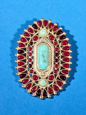 a close up of a red and green broochle on a blue surface