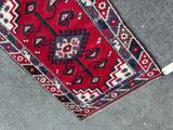 a red and blue rug on the floor with a white cord