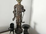 une statue posée sur une table, à côté d'autres objets