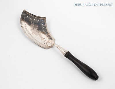 une vieille spatule argentée et noire posée sur une surface blanche