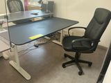 a black office chair sitting in front of a computer desk