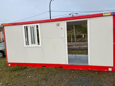 une maison préfabriquée rouge et blanche posée dans l'herbe