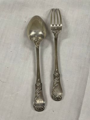 une paire de cuillères et une fourchette plaquées argent posées sur une nappe blanche