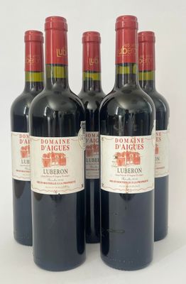 quatre bouteilles de vin rouge sont alignées sur une surface blanche