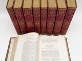 six old books sitting on top of each other on a white surface