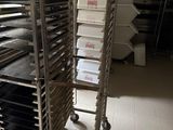 Plusieurs plateaux de nourriture sont empilés sur un chariot dans une cuisine