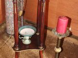 a small table with a clock on it next to a candle