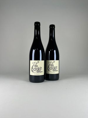 two bottles of red wine sitting on top of a white table