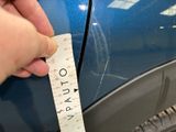 a hand holding a measuring tape next to a blue car