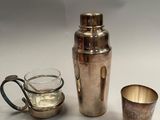 two cups and a shaker sitting on a table next to each other