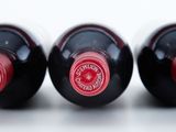 three bottles of red wine are lined up on a white surface