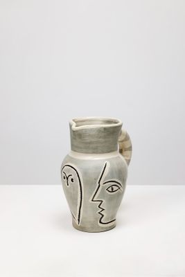 un vase orné d'un visage, posé sur une table