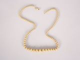 gold beaded necklace on a white background with a heart