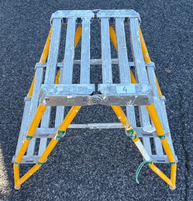 un escabeau jaune et argent posé par terre