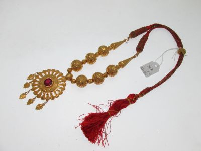 une paire de colliers dorés et rouges ornés de pompons, sur un fond blanc