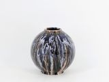 un vase noir et blanc posé sur une surface blanche