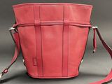 red leather purse with strap on grey surface with gray background